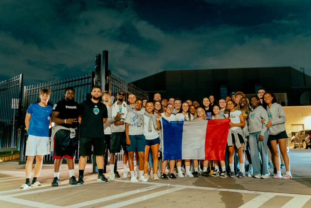 Groupe de participants du Combine Elite Camp après un match WNBA, tenant un drapeau français.